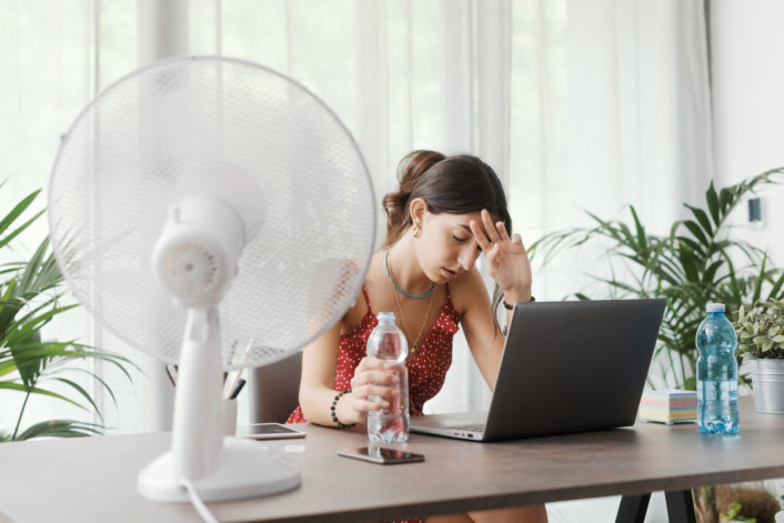 Woman cooling herself with an electric fan