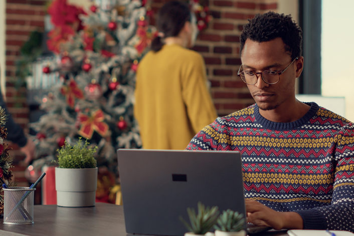 Company employee using laptop in christmas decorated office
